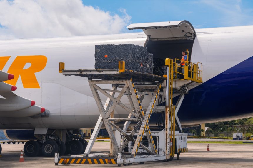 Imagem colorida mostra cargas sendo transportadas no Aeroporto de Manaus