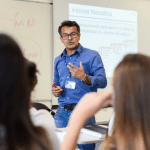 Imagem colorida mostra professor dando aula em sala com estudantes atentos para falar sobre Prova Nacional para Contratação de Professores