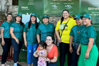 Imagem colorida mostra comunitários da Vila de Paricatuba em frente a banner do Projeto Viva Paricatuba