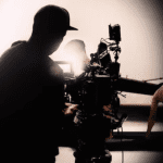 Imagem em tons de preto de branco mostra produção de cinema por trás das câmeras