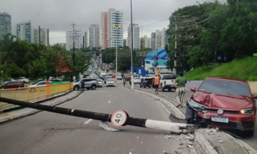 Acidente de carro em via urbana, com veículo danificado e poste caído.