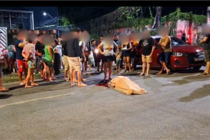 Acidente de trânsito com vítima fatal em avenida, com pessoas ao redor e carro vermelho.