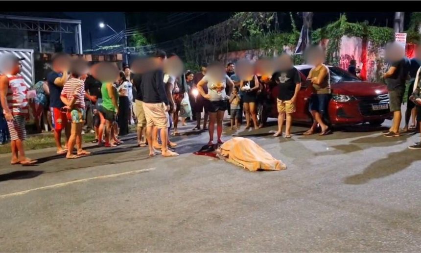 Acidente de trânsito com vítima fatal em avenida, com pessoas ao redor e carro vermelho.