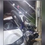Acidente de trânsito: motocicleta colide com carro, vidro quebrado e moto em cima.