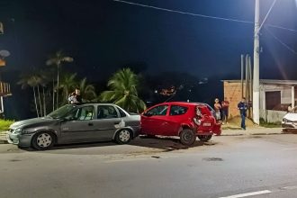 Acidente de trânsito na Avenida do Turismo envolvendo dois carros, com pessoas no local e luzes noturnas.