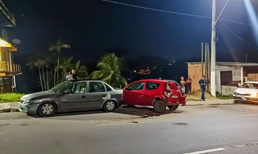 Acidente de trânsito na Avenida do Turismo envolvendo dois carros, com pessoas no local e luzes noturnas.