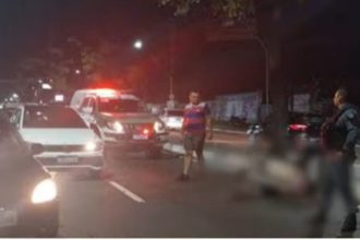 Acidente de trânsito noturno: homem atropelado na rua com ambulância no local.