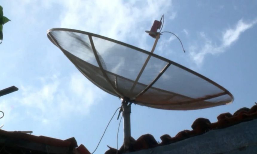 Antena parabólica tradicional no telhado sob céu azul com nuvens