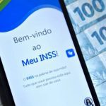 Aplicativo Meu INSS em um smartphone com notas de dinheiro ao fundo