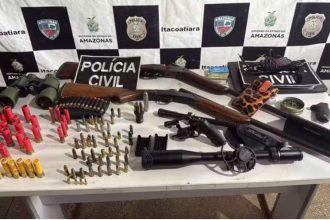 Apreensão de armas e munições em Itacoatiara, Amazonas. Pistola, espingardas, binóculos e cartuchos sobre uma mesa.