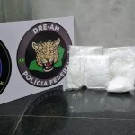 Apreensão de drogas pela Polícia Federal no Aeroporto de Manaus, com sacos plásticos de substância suspeita e distintivos.