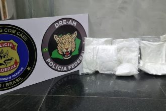 Apreensão de drogas pela Polícia Federal no Aeroporto de Manaus, com sacos plásticos de substância suspeita e distintivos.