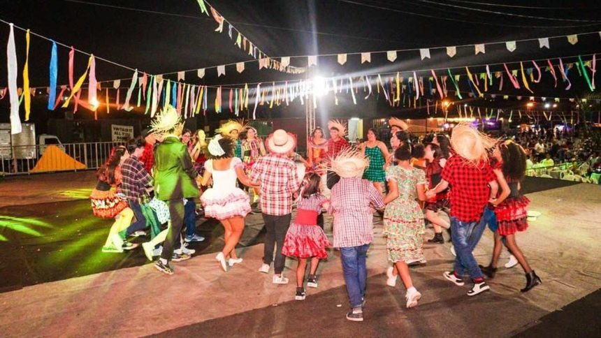 Arraial com dança folclórica em festa junina, com pessoas vestidas a caráter e decoração festiva.