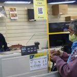 Atendimento em agência dos Correios: funcionária atende cliente com máscara