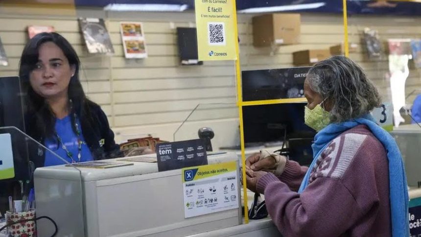 Atendimento em agência dos Correios: funcionária atende cliente com máscara