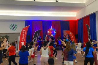 Aulão de Boi Bumbá no Shopping Ponta Negra, com pessoas dançando e banda no palco.