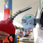 Bico de gasolina sendo inserido no tanque de um carro para abastecer.