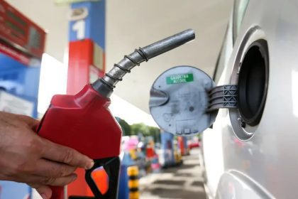 Bico de gasolina sendo inserido no tanque de um carro para abastecer.