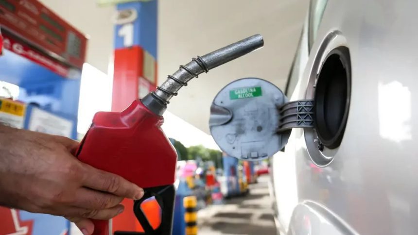 Bico de gasolina sendo inserido no tanque de um carro para abastecer.