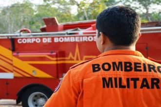 Bombeiro militar em frente a um caminhão do corpo de bombeiros.