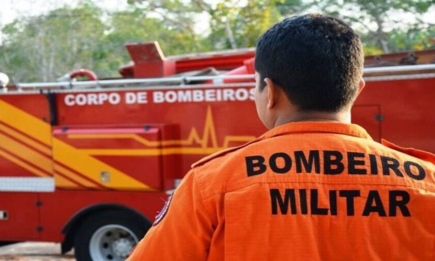 Bombeiro militar em frente a um caminhĂŁo do corpo de bombeiros.