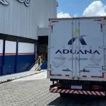 Caminhão do Grupo Aduana estacionado em frente a um prédio.