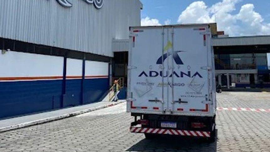 Caminhão do Grupo Aduana estacionado em frente a um prédio.