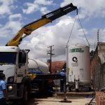 Caminhão Dunloc com guindaste içando tanque de oxigênio líquido White Martins.