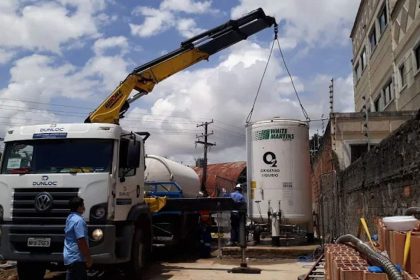 Caminhão Dunloc com guindaste içando tanque de oxigênio líquido White Martins.