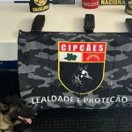 Cão farejador da PMAM ao lado de material apreendido em ação contra o tráfico de drogas.