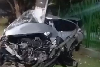 Carro destruído após colidir com poste, motorista preso