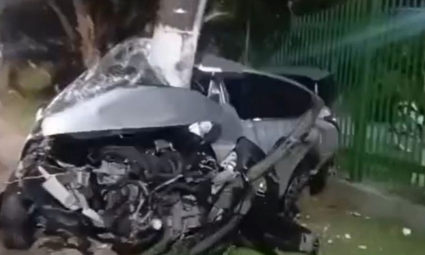 Carro destruído após colidir com poste, motorista preso