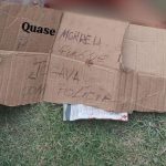 Cartaz de papelão com escrita sobre crime em Manaus: 'Quase morri porque jogava com a polícia'.