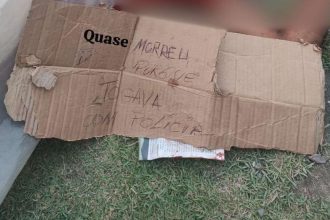 Cartaz de papelão com escrita sobre crime em Manaus: 'Quase morri porque jogava com a polícia'.