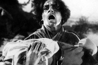 Cena de filme em preto e branco com mulher segurando tecido e expressão de choque.