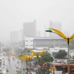 Chuvas em Manaus: vista de avenida com postes de luz e edifícios ao fundo.