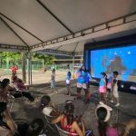 Crianças assistem a um filme de circo em um evento ao ar livre