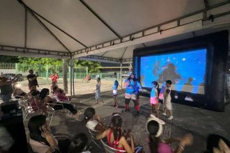 Crianças assistem a um filme de circo em um evento ao ar livre