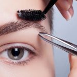 Design de sobrancelhas sendo feito com pinça e escova