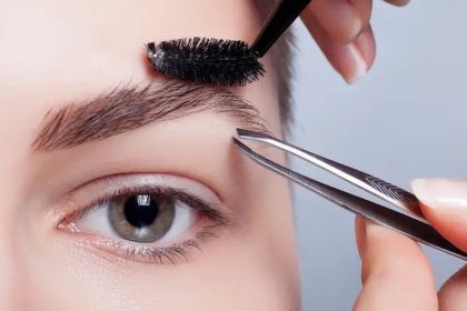 Design de sobrancelhas sendo feito com pinça e escova