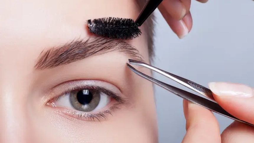Design de sobrancelhas sendo feito com pinça e escova