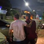 Dois homens em cena noturna, possivelmente após uma prisão.