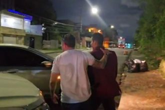 Dois homens em cena noturna, possivelmente após uma prisão.