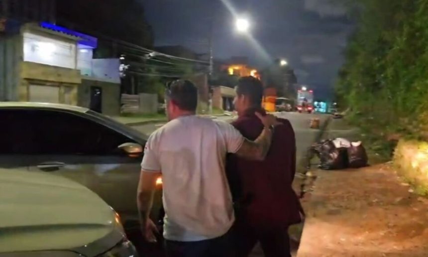 Dois homens em cena noturna, possivelmente após uma prisão.