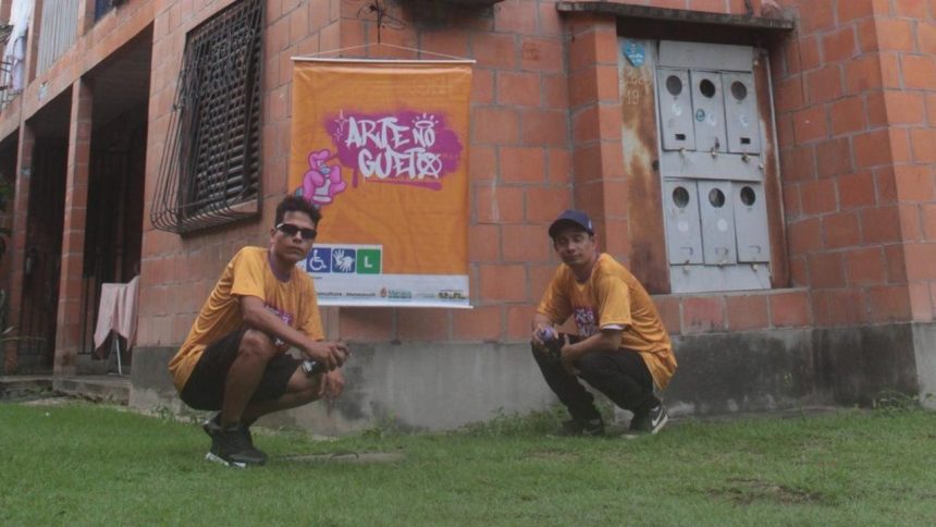 Dois homens em frente a um grafite, em um evento de arte de rua.