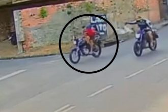Dois homens em motocicletas em uma rua, possivelmente envolvidos em crime.