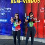 Duas mulheres segurando copos promocionais em evento da Sicredi Parintins.