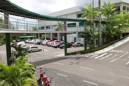 Estacionamento em frente à Tapajós Distribuidora, Manaus, com carros e passarela coberta.