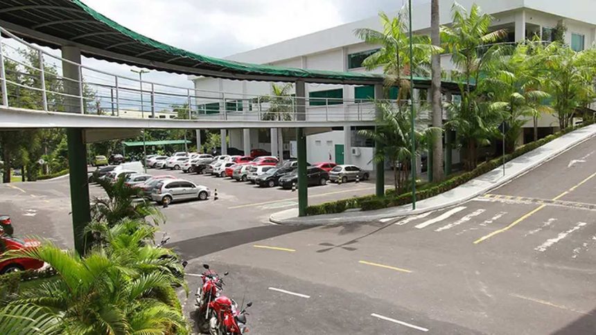 Estacionamento em frente à Tapajós Distribuidora, Manaus, com carros e passarela coberta.