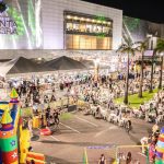 Evento gastronômico 'Arraial Chefs de Ponta' em frente ao Shopping Ponta Negra em Manaus, com barracas de comida e diversão.